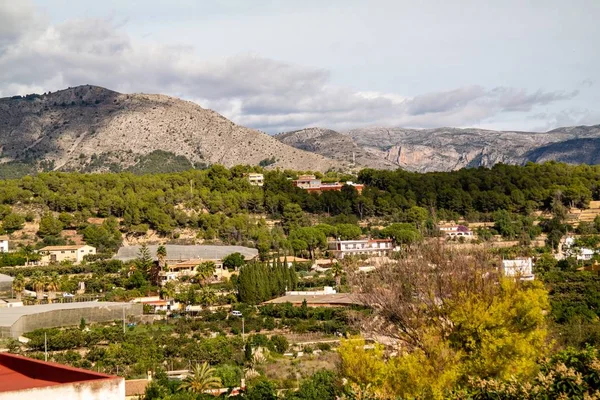 Bird 's eye view of lush nature and buildings of Polop city in Spain με φόντο τα βουνά — Φωτογραφία Αρχείου