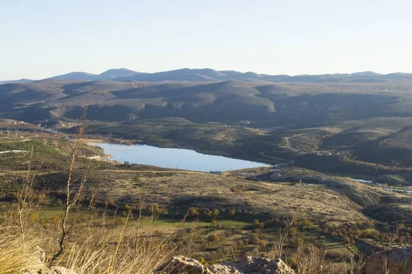 Vue panoramique d'un lac entre des collines onduleuses sous un ciel nuageux — Photo