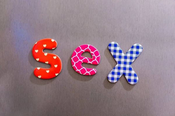 Sexo palavra feito de letras magnéticas coloridas em um fundo marrom — Fotografia de Stock
