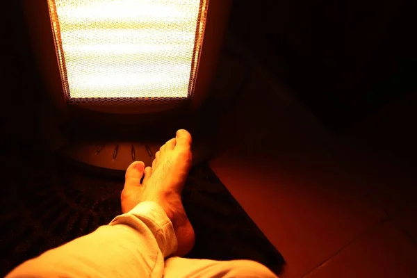 Colpo ad angolo alto di una persona che allunga i piedi davanti a un riscaldatore in una stanza — Foto Stock