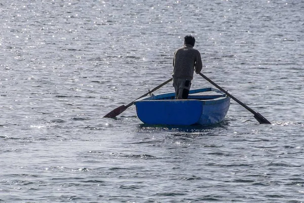 Person auf einem blauen Ruderboot auf der ruhigen Wasseroberfläche — Stockfoto