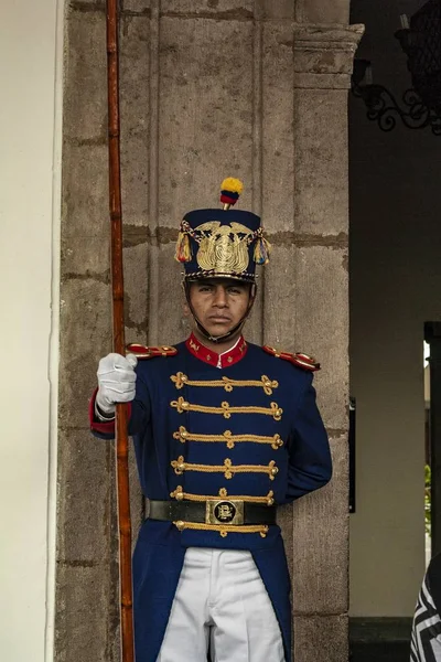 Pionowe ujęcie strażnika ekwadorskiego rządu stojącego przed betonową ścianą — Zdjęcie stockowe