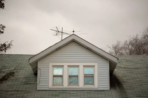 Grünes Dach eines Hauses mit einem Fenster darauf, in dem sich Reflexion spiegelt — Stockfoto