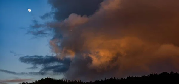 Снимок дышащих облаков в вечернем небе с луной слева — стоковое фото