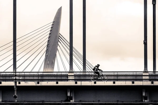 Wide angle shot of a man driving a bicycle on a bridge — Stock Photo, Image