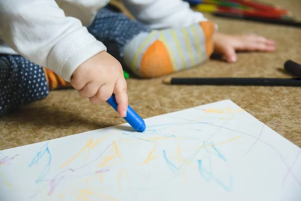 Desenho de bebê pequeno com um lápis de cera azul em um papel — Fotografia de Stock