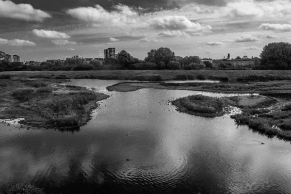 Ampio angolo buio colpo di acqua e paesaggio di fronte a una città sotto un cielo nuvoloso — Foto Stock