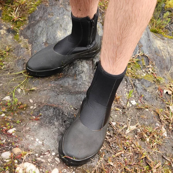 Colpo ad angolo alto dei piedi di una persona che indossa stivali in piedi sulle rocce — Foto Stock