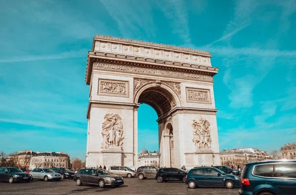 Vítězný oblouk obklopený auty pod modrou oblohou v Paříži ve Francii — Stock fotografie