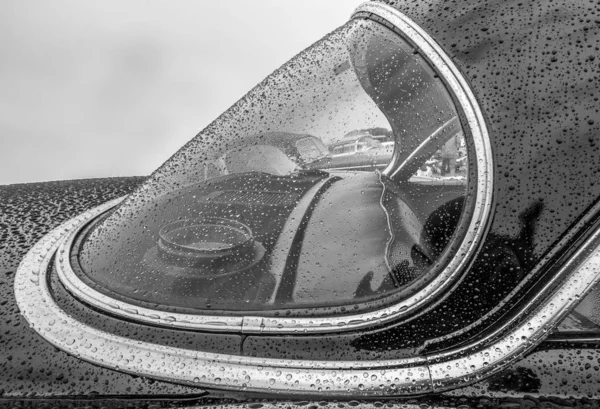 Foto a escala de grises de la parte delantera de un coche cubierto de gotas de lluvia — Foto de Stock