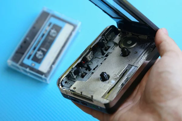 Duże ujęcie osoby trzymającej magnetofon kasetowy z kasetą na niebieskiej powierzchni — Zdjęcie stockowe