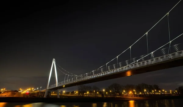 Alacsony szögű felvétel egy nagy hídról, ami éjszaka a víz felett halad. — Stock Fotó