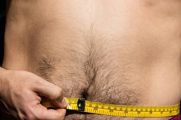 Encerramento tiro de uma pessoa medindo sua cintura com uma fita métrica — Fotografia de Stock