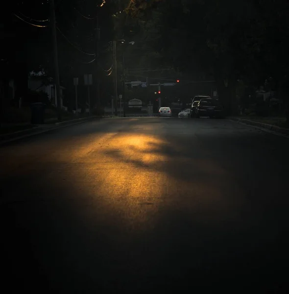 Gambar vertikal dari jalan gelap dengan bayangan cahaya jalan dan mobil — Stok Foto