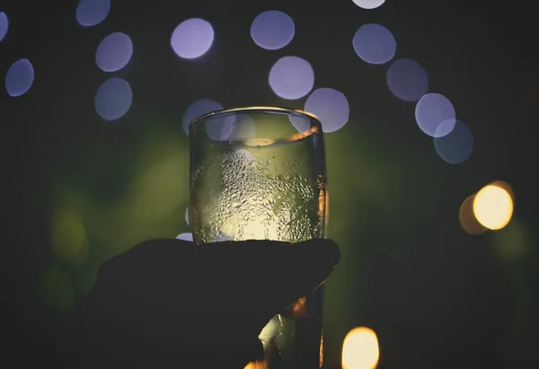 Messa a fuoco selettiva di una persona che tiene un bicchiere con luci sfocate sullo sfondo — Foto Stock