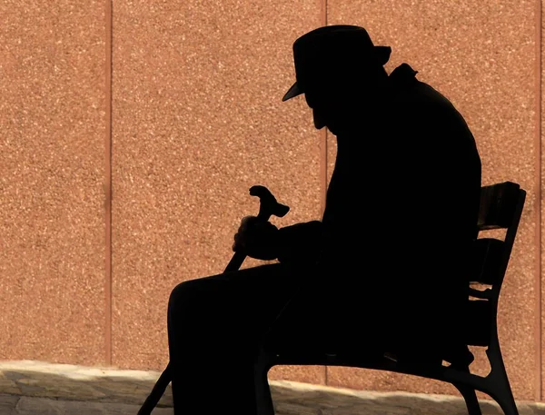 Verbazingwekkend shot van een silhouet van een man en het vasthouden van een wandelstok terwijl zittend op een stoel — Stockfoto