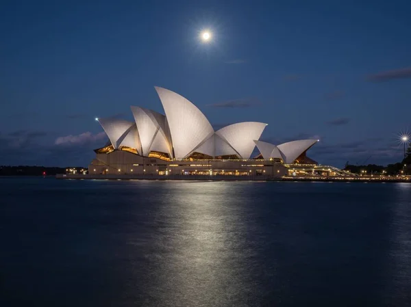 Magníficas vistas nocturnas de la Ópera de Sydney, Australia, con una luna llena que brilla por encima. — Foto de Stock
