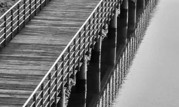 Foto en blanco y negro de una pasarela portuaria cerca de la playa. — Foto de Stock