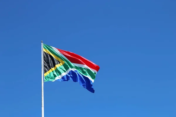 Bajo ángulo de tiro de la bandera de Sudáfrica en el viento bajo el cielo azul claro —  Fotos de Stock