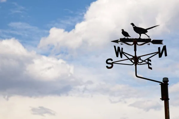 Wind vane isolated on a cloudy sky background. Wind direction concept image