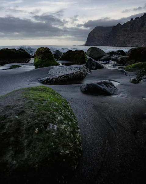 Вертикальный высокий угол съемки москитных камней на пляже в темный облачный день — стоковое фото