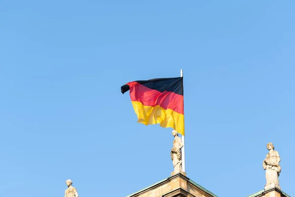 Σημαία της Γερμανίας φτερουγίζει στον άνεμο κάτω από έναν γαλάζιο ουρανό — Φωτογραφία Αρχείου