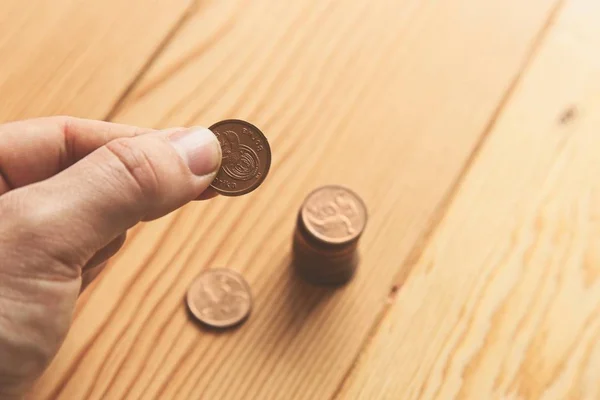 Colpo ad angolo alto di una persona che tiene una moneta su una superficie di legno — Foto Stock