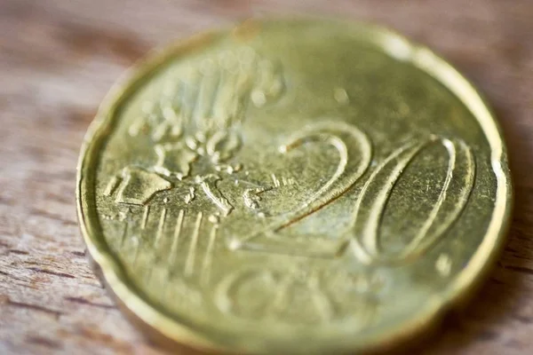 High angle closeup shot of a golden twenty-cent coin on a wooden surface with blurred background