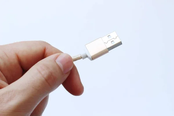 Close-up van een persoon die een USB-kabel met een witte achtergrond vasthoudt — Stockfoto
