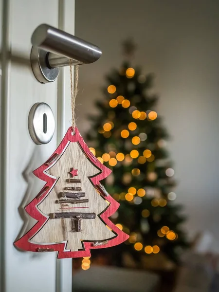 Ornamento de árbol colgando de la nube de la puerta con un árbol de Navidad en el fondo borroso. —  Fotos de Stock