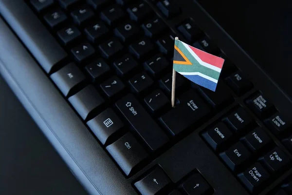 Foto de gran angular de una pequeña bandera de Sudáfrica en un teclado de ordenador negro —  Fotos de Stock
