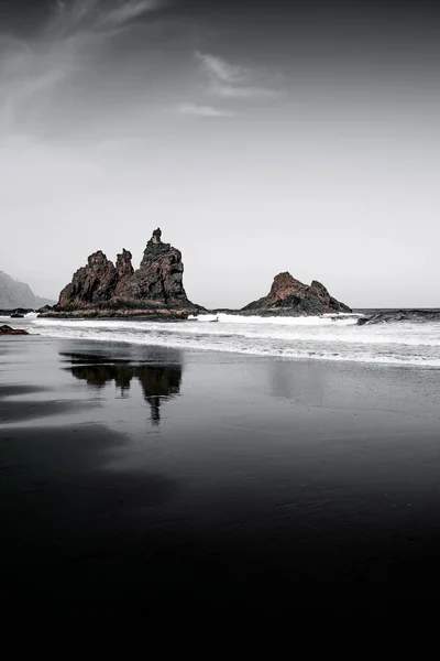 Tiro vertical de formações rochosas no mar com reflexos na água — Fotografia de Stock