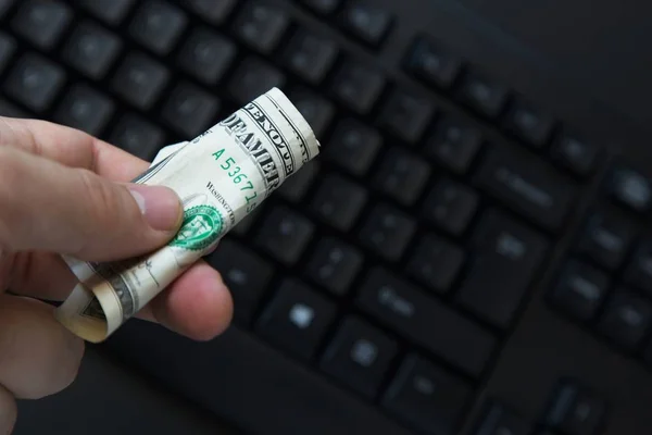 Duże zbliżenie ujęcia osoby trzymającej banknot dolarowy nad czarnym laptopem — Zdjęcie stockowe