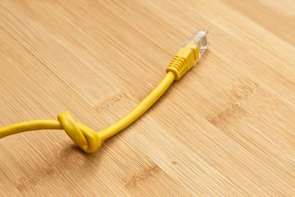 Hög vinkel skott av en knuten gul kabel på en träyta — Stockfoto