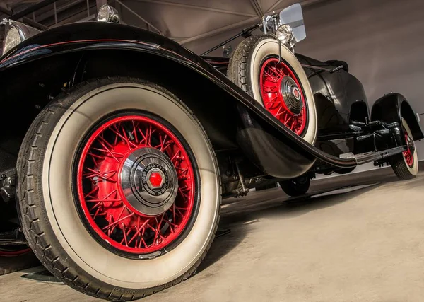 Foto de ángulo bajo de un vehículo negro con ruedas rojas estacionadas en un suelo gris. — Foto de Stock