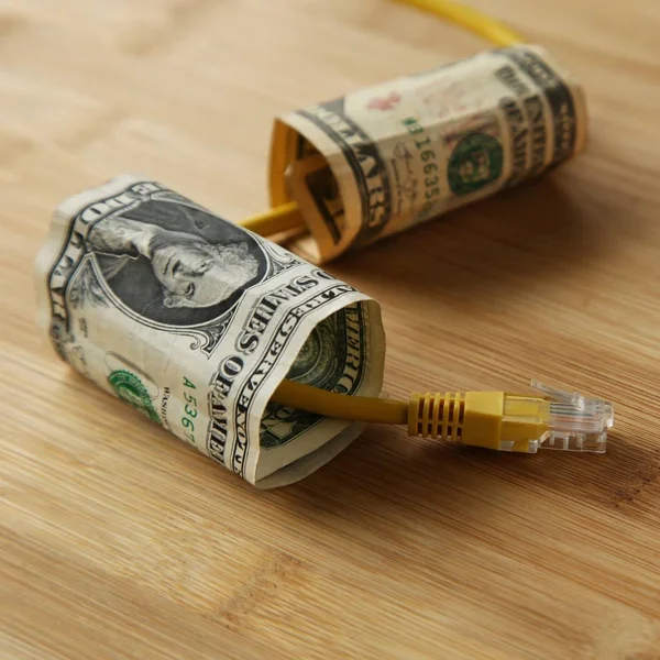 Zbliżenie kabla LAN przechodzącego przez banknoty dolarowe na drewnianej powierzchni — Zdjęcie stockowe