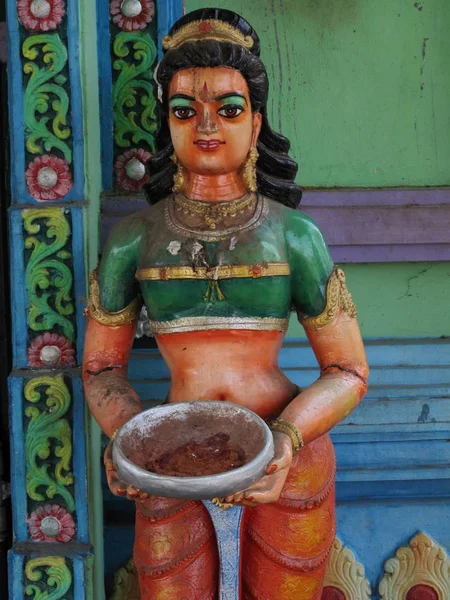 Vertical shot of a Hindu statue near a colorful wall — 스톡 사진
