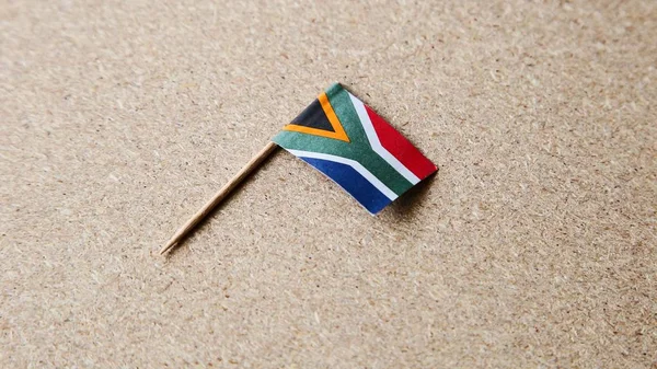 Foto en ángulo alto de una pequeña bandera sudafricana sobre una superficie de madera —  Fotos de Stock