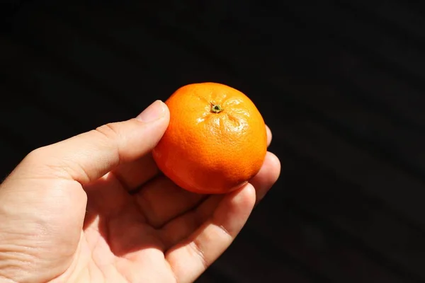 Eine Großaufnahme Einer Person Die Eine Mandarine Über Einem Dunklen — Stockfoto