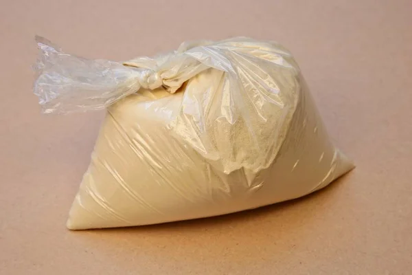 High angle shot of a plastic bag full of flour on a pink surface — ストック写真