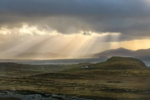 Beautiful shot of the fields and mountains with sun rays shining through clouds — Stock Photo, Image