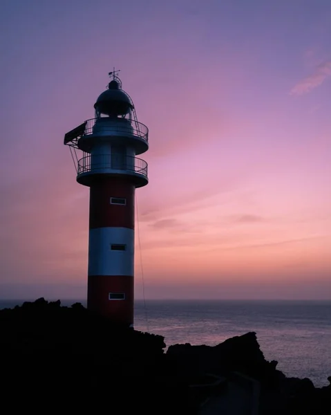 Plan vertical d'un phare sur le rivage de la mer avec le ciel violet en arrière-plan — Photo