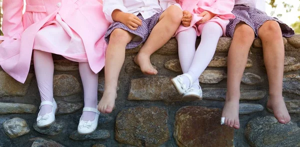 Legs of kids sitting on a wall under the sunlight - a nice picture for backgrounds and wallpapers — Stock Photo, Image