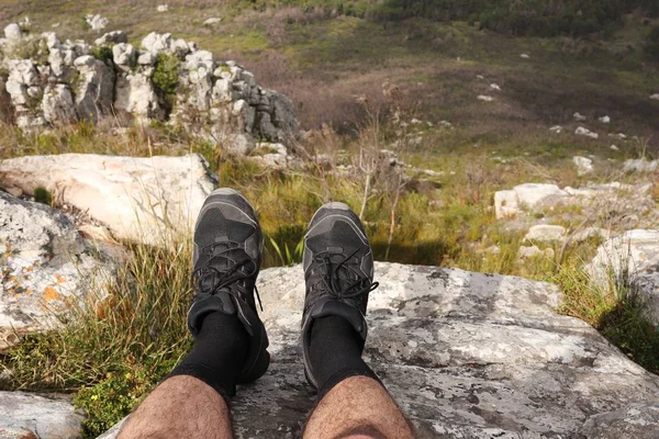 Високий кутовий знімок ноги людини, що сидить на скелі над долиною — стокове фото