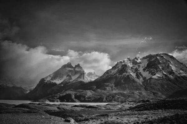 Foto in scala di grigi delle rocce innevate nella regione della Patagonia in Cile sotto il cielo nuvoloso — Foto Stock