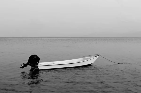 Graustufenaufnahme eines leeren Motorbootes auf der ruhigen Wasseroberfläche — Stockfoto