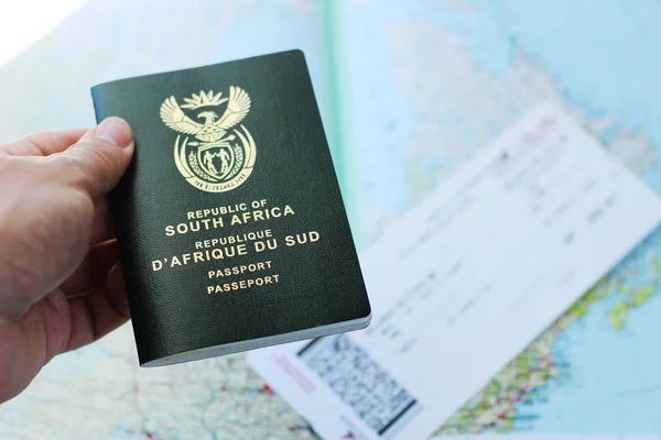 Uçak bileti ve coğrafi harita üzerinde pasaport taşıyan birinin yüksek açılı görüntüsü. — Stok fotoğraf