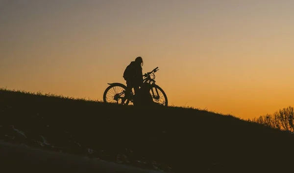 Silhouette d'une personne en vélo sur un terrain lors d'un coucher de soleil — Photo