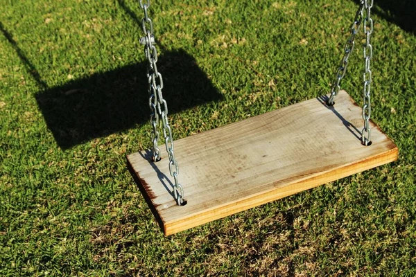 Hoge hoek shot van een van hout swing overheen een gras bedekt veld — Stockfoto