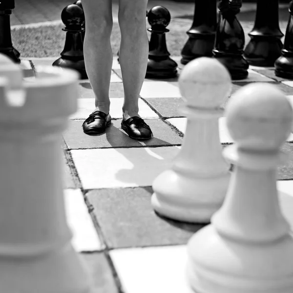 Grey scale shot of a female standing in the middle of a big chess board — Stock Photo, Image